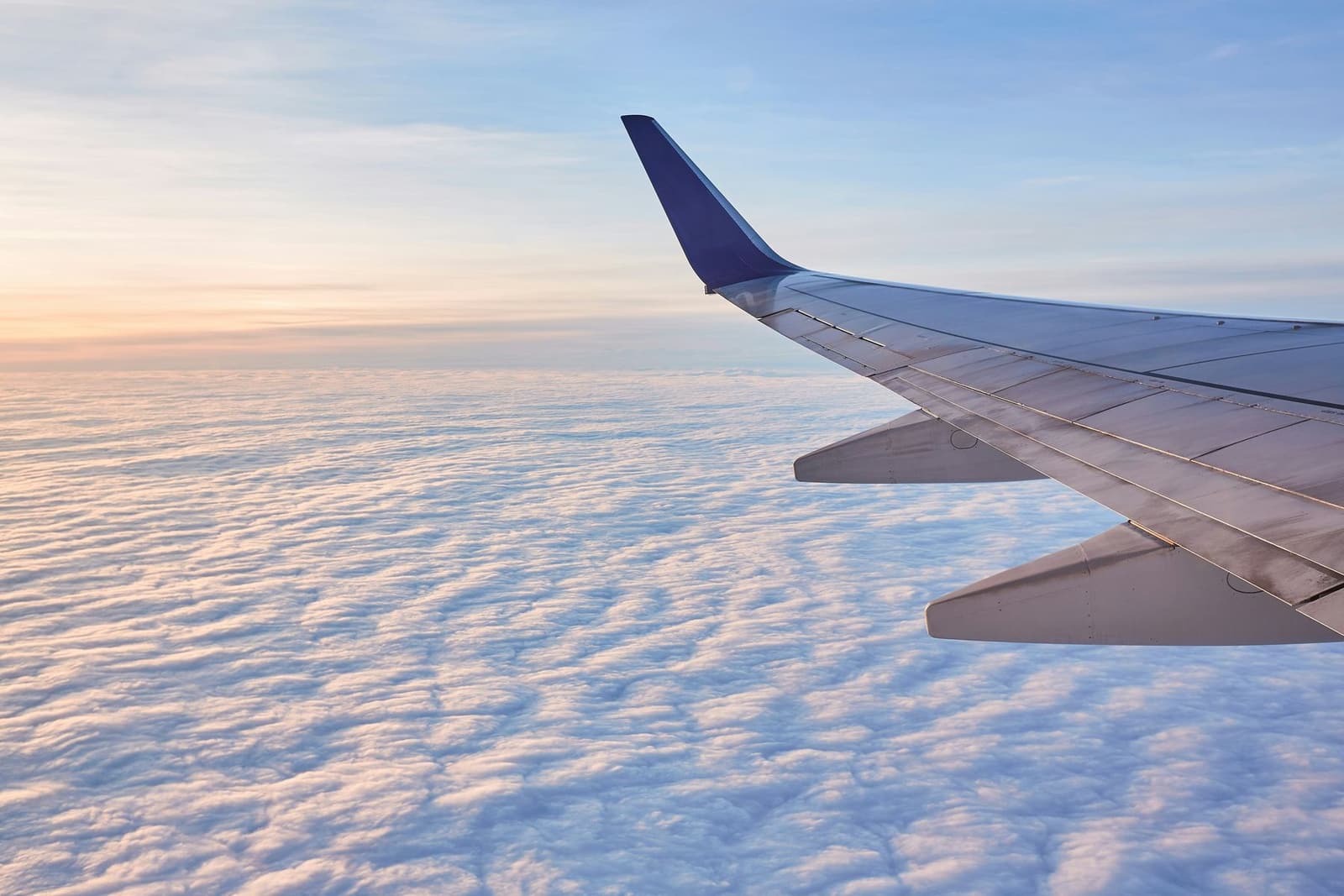 View of an aircraft wing above the clouds at sunrise