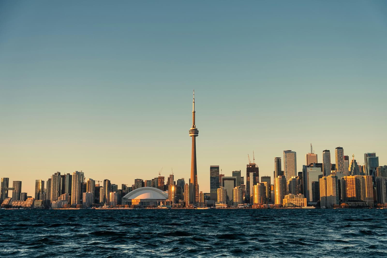 The Toronto skyline and CN Tower at golden hour, seen across Lake Ontario